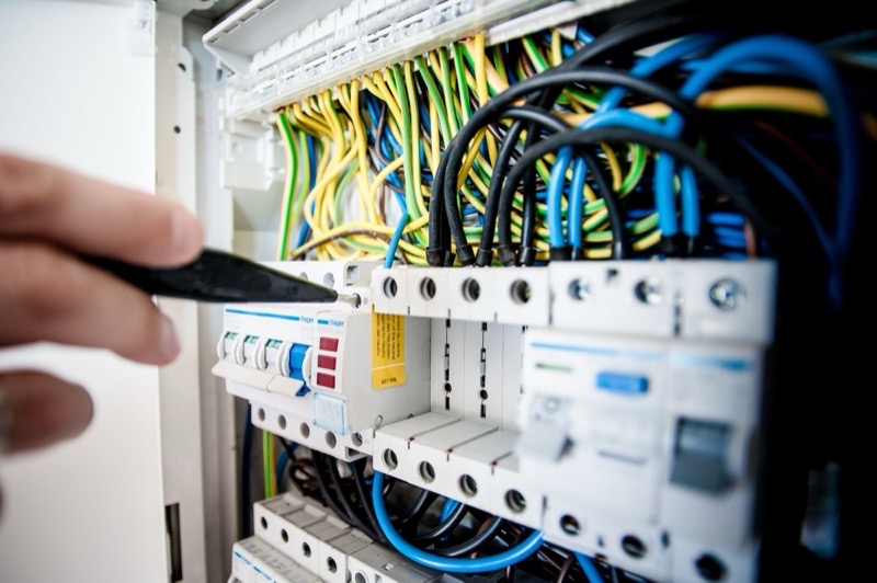 A hand working among circuit breakers in a consumer unit